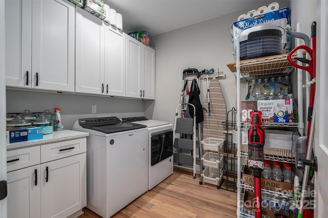 laundry room featuring cabinets, light hardwood / wood-style flooring, and washer and clothes dryer