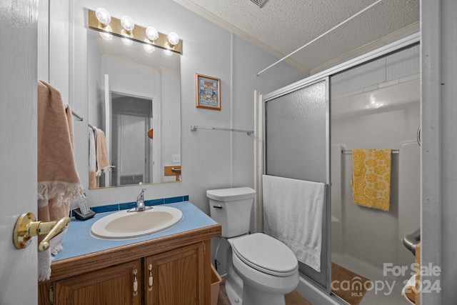 bathroom with vanity, a shower with shower door, a textured ceiling, and toilet