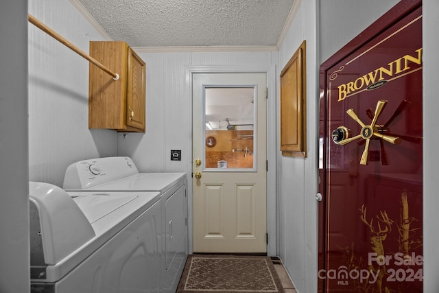 clothes washing area with cabinets, a textured ceiling, washing machine and dryer, and crown molding