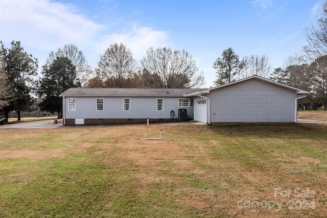 rear view of property with a yard, a garage, and central AC unit