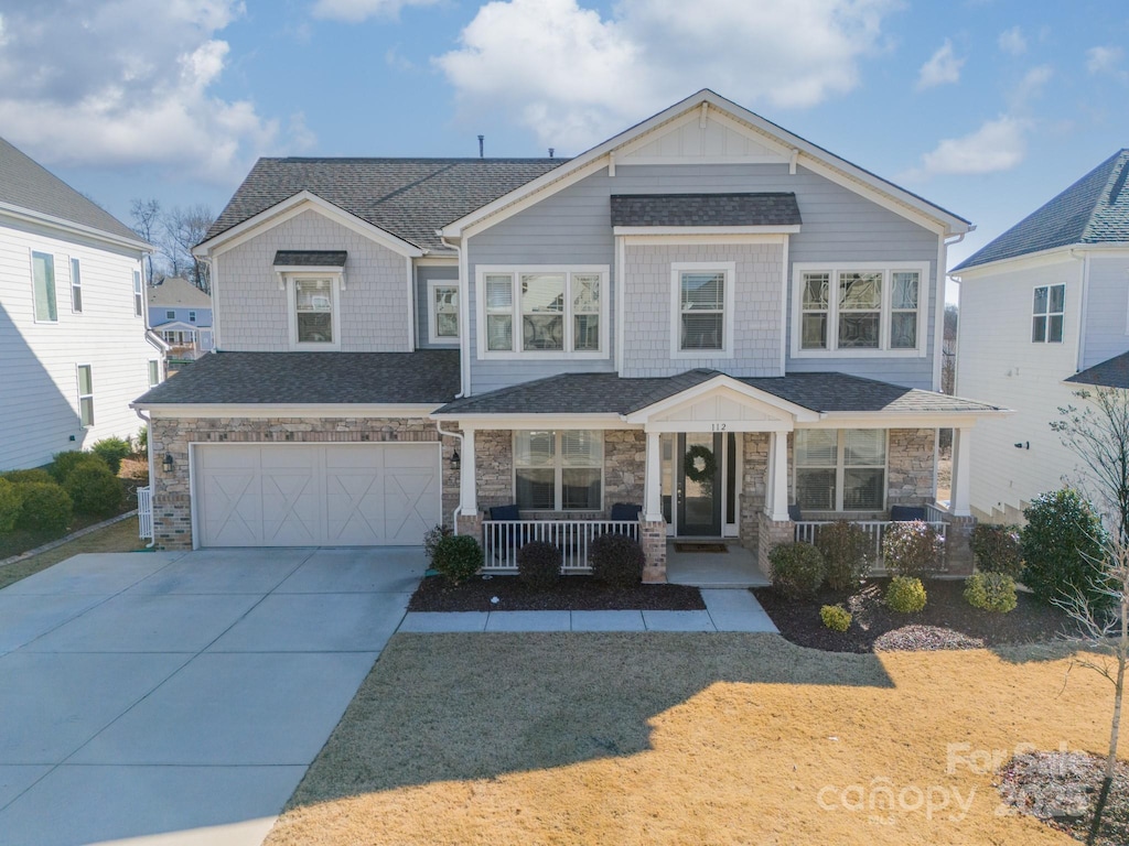 view of front of house with covered porch, a garage, and a front lawn