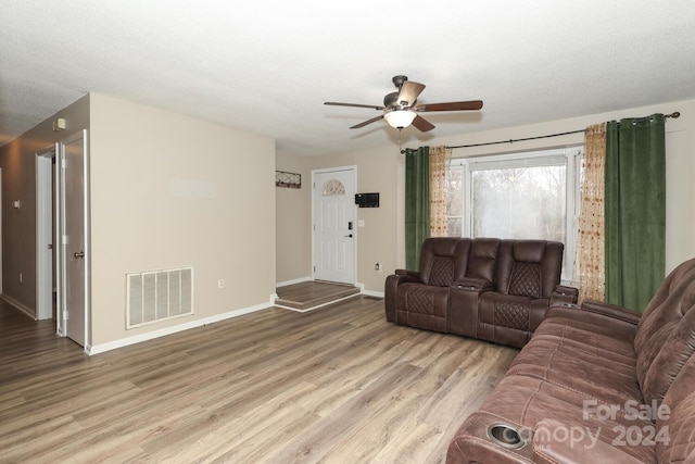 living room with a textured ceiling, light hardwood / wood-style floors, and ceiling fan