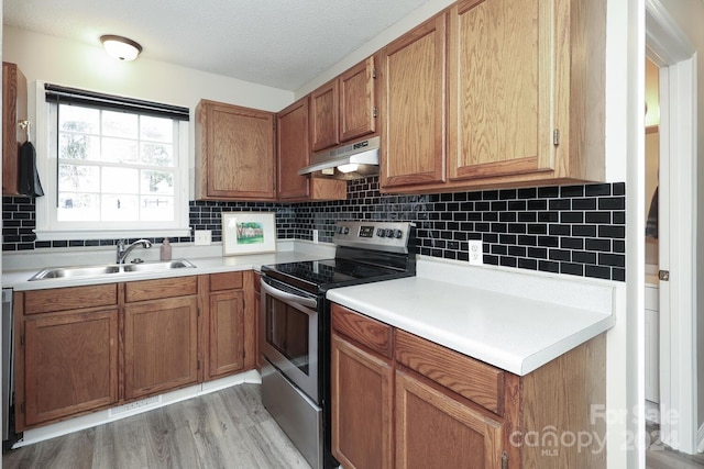 kitchen with electric range, light hardwood / wood-style floors, backsplash, and sink