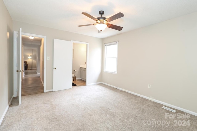 unfurnished bedroom with ceiling fan, light colored carpet, and ensuite bathroom