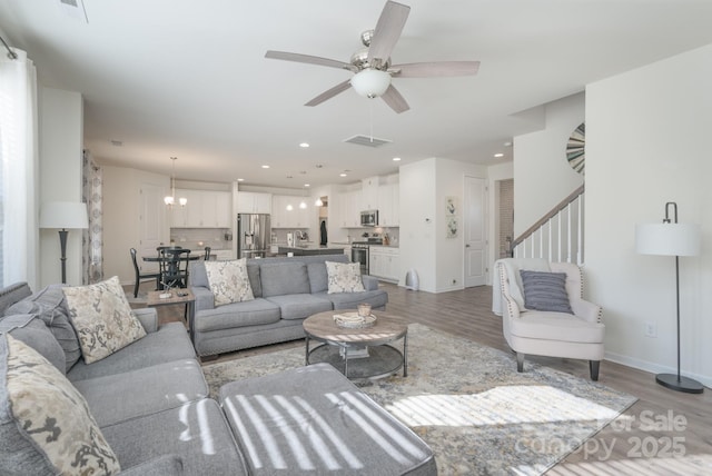 living room featuring wood-type flooring and ceiling fan with notable chandelier