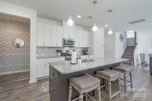 kitchen with white cabinets, pendant lighting, and stainless steel appliances