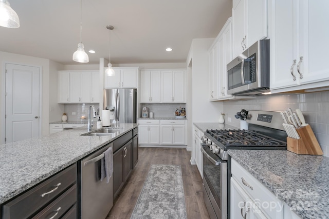 kitchen with sink, light stone countertops, decorative light fixtures, white cabinetry, and stainless steel appliances