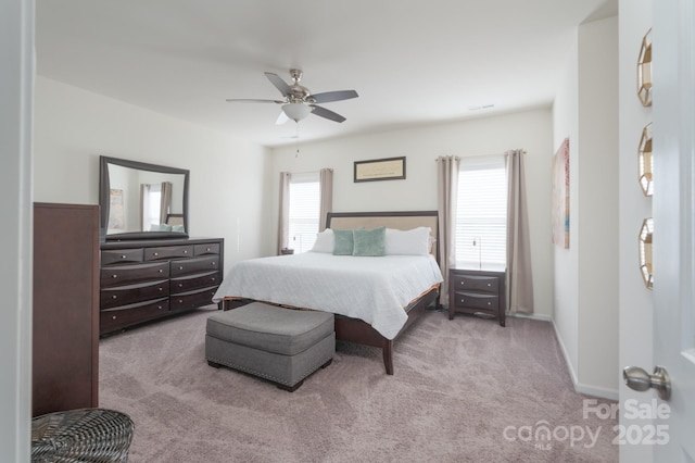 bedroom with ceiling fan, light carpet, and multiple windows