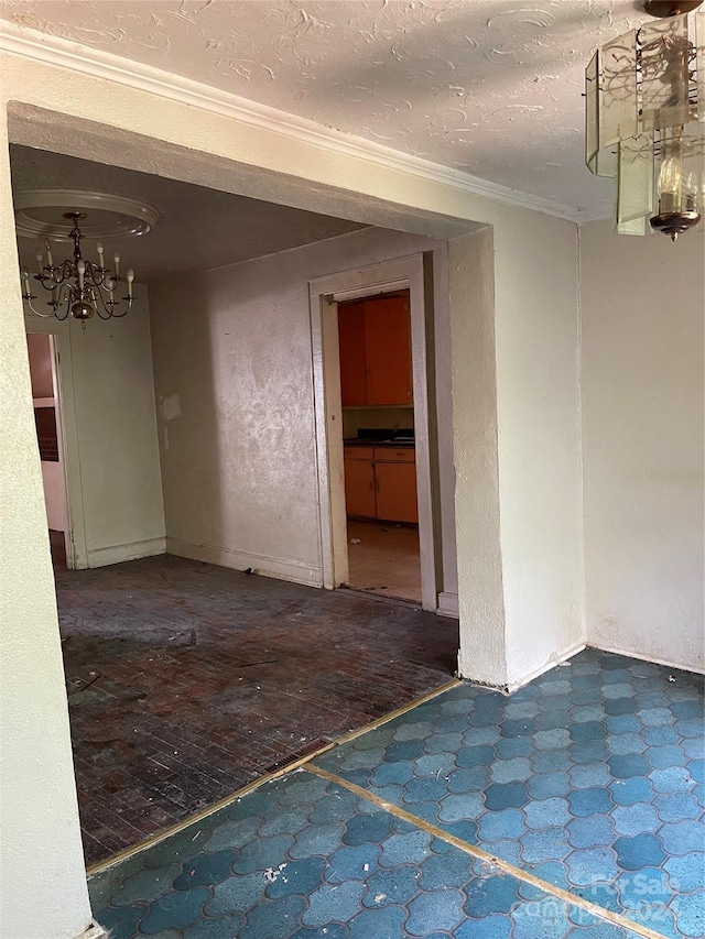 empty room featuring ornamental molding, a textured ceiling, and a notable chandelier