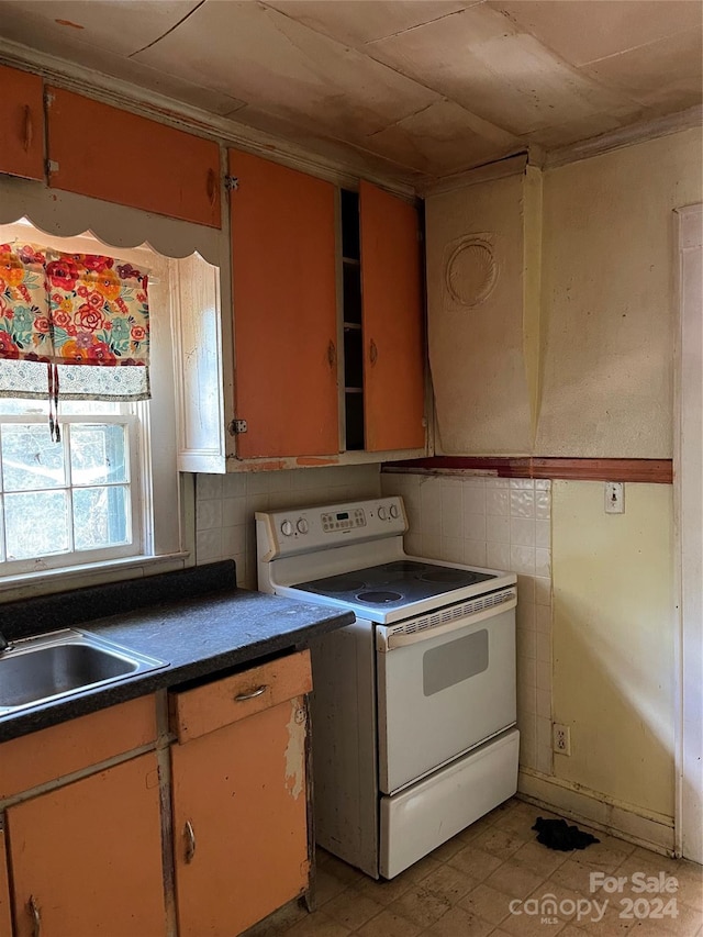 kitchen featuring sink, white electric range oven, and tile walls