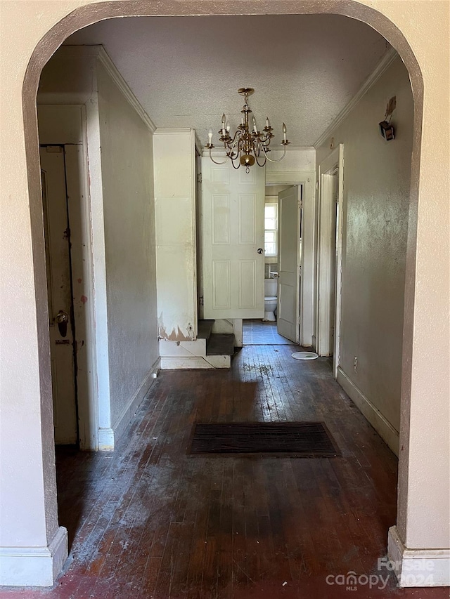 hallway featuring dark hardwood / wood-style flooring, a chandelier, a textured ceiling, and ornamental molding