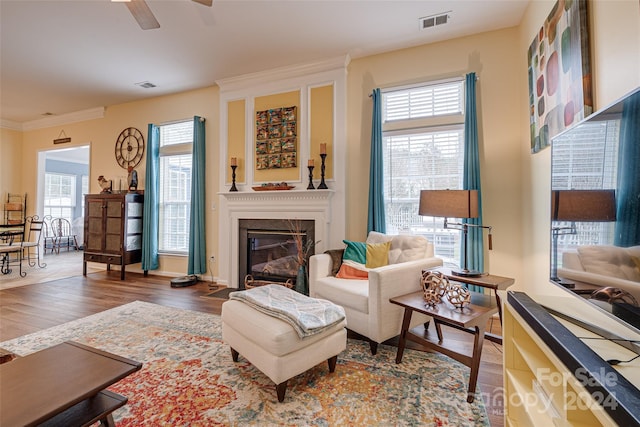 living room with ceiling fan, ornamental molding, and dark wood-type flooring