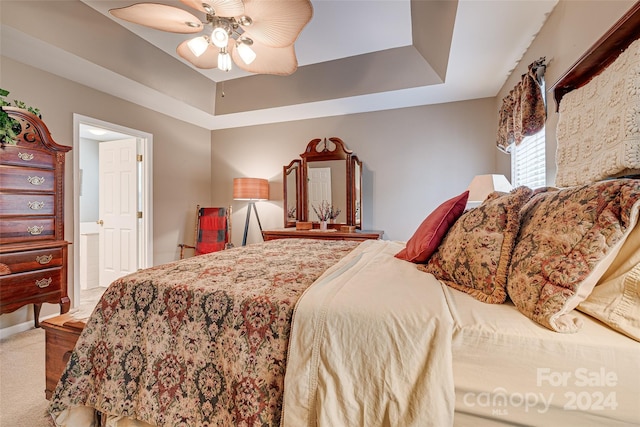 bedroom with a tray ceiling, ceiling fan, and carpet