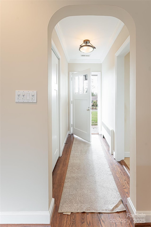 doorway to outside featuring radiator heating unit, wood-type flooring, and ornamental molding