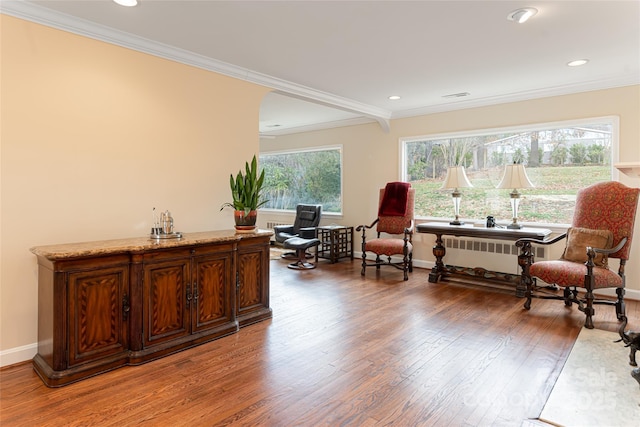 sitting room with radiator heating unit, crown molding, and hardwood / wood-style floors