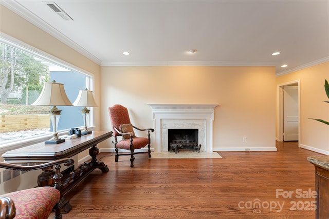 living area with a fireplace, crown molding, and hardwood / wood-style floors