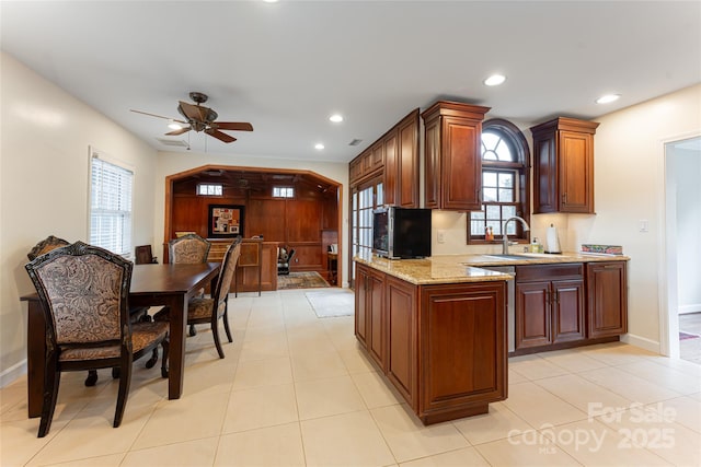 kitchen featuring light stone countertops, light tile patterned floors, ceiling fan, and sink