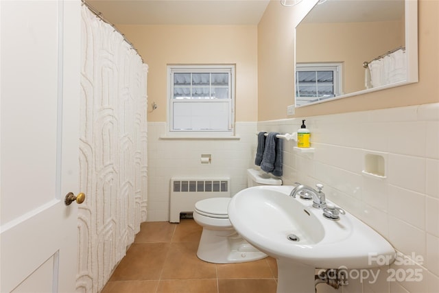 bathroom with tile patterned floors, sink, tile walls, radiator heating unit, and toilet