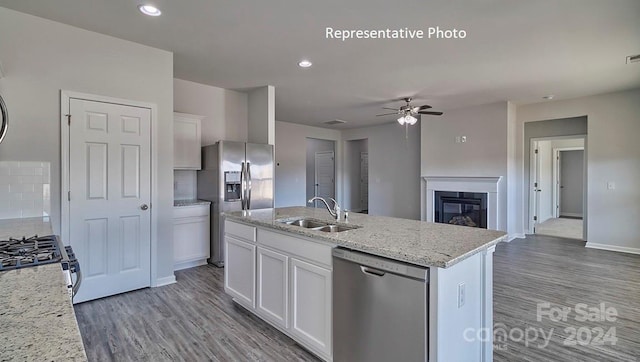 kitchen featuring white cabinets, a center island with sink, sink, light stone countertops, and stainless steel appliances