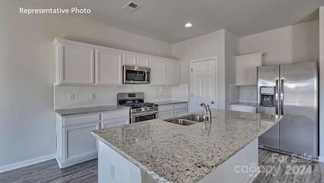 kitchen featuring a kitchen island with sink, sink, decorative backsplash, appliances with stainless steel finishes, and white cabinetry