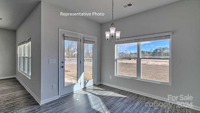 unfurnished dining area featuring a chandelier and dark hardwood / wood-style floors