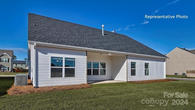 rear view of house with central AC unit and a lawn