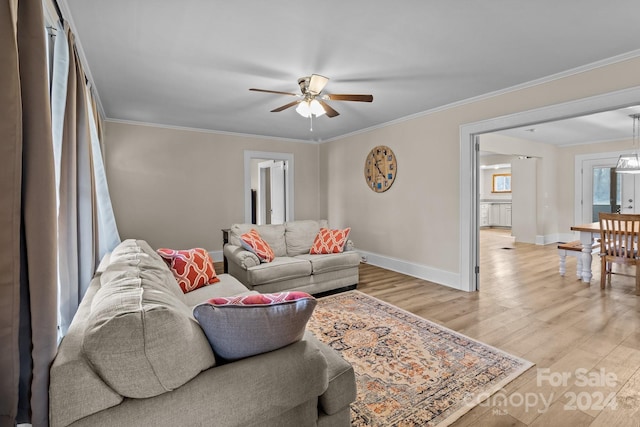 living room featuring light hardwood / wood-style flooring, ceiling fan, and crown molding