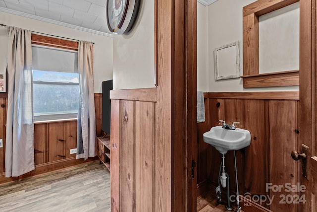 bathroom featuring crown molding, hardwood / wood-style floors, and wood walls