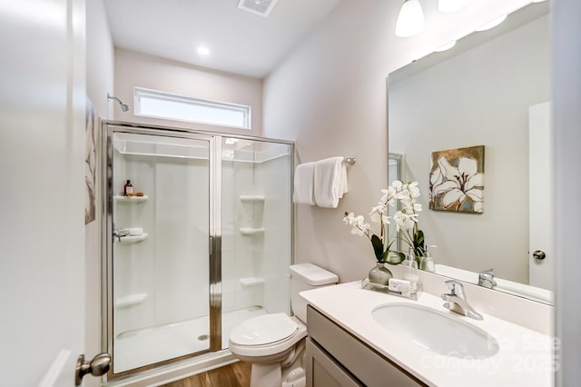 bathroom featuring vanity, wood finished floors, visible vents, a shower stall, and toilet