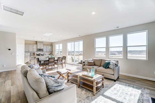 living area featuring baseboards, visible vents, and light wood finished floors