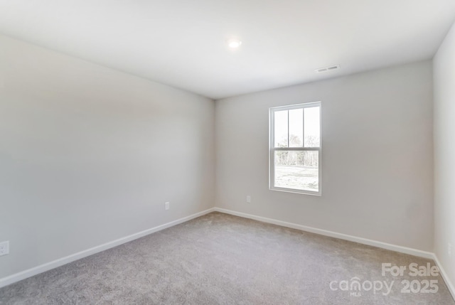 empty room featuring visible vents, light colored carpet, and baseboards