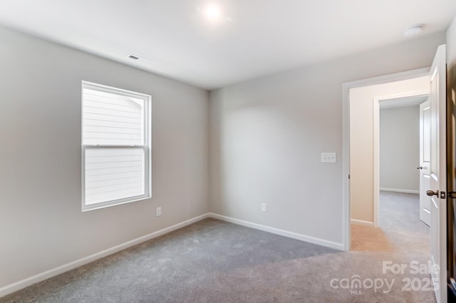 empty room featuring baseboards, visible vents, and light carpet