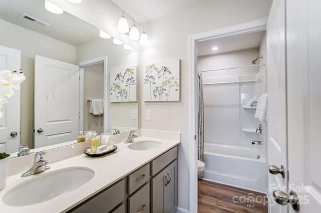 bathroom featuring toilet, wood finished floors, visible vents, and a sink