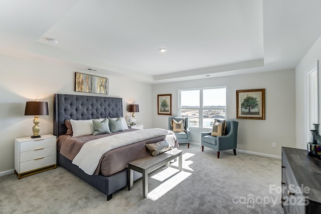 bedroom featuring a raised ceiling, baseboards, and light carpet