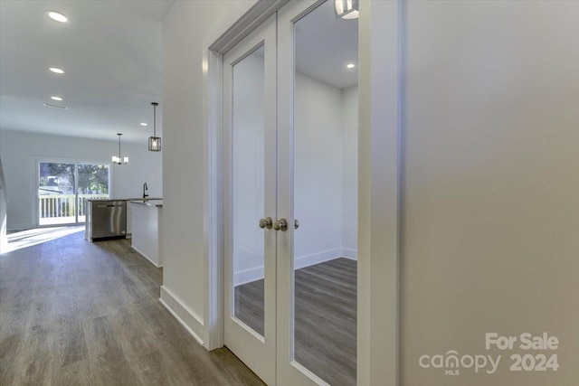 hallway featuring a chandelier, wood-type flooring, french doors, and sink