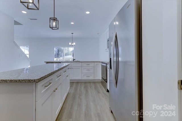 kitchen featuring white cabinetry, a center island, stainless steel appliances, pendant lighting, and light hardwood / wood-style floors