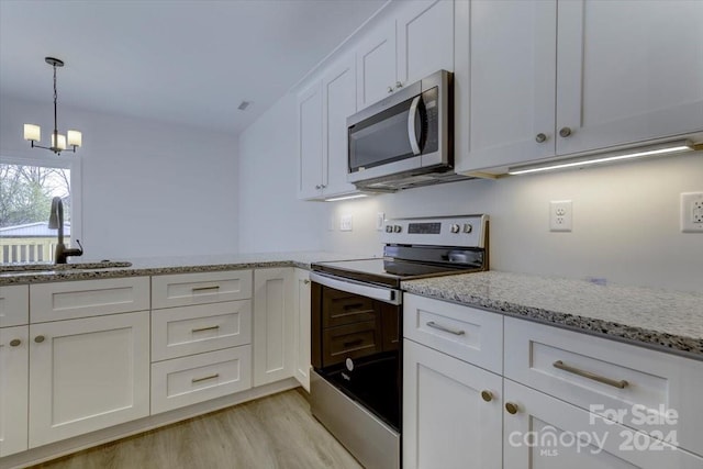 kitchen featuring appliances with stainless steel finishes, light stone counters, sink, a notable chandelier, and white cabinets