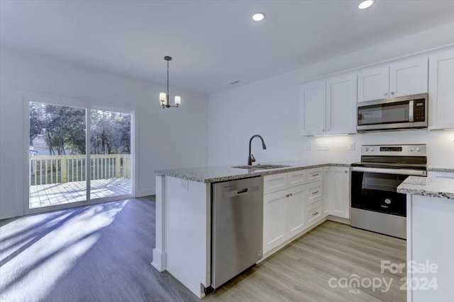 kitchen with decorative light fixtures, white cabinetry, and appliances with stainless steel finishes