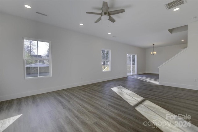 unfurnished living room featuring ceiling fan with notable chandelier and dark wood-type flooring