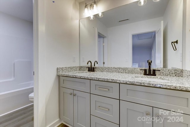 full bathroom with bathtub / shower combination, wood-type flooring, vanity, and toilet