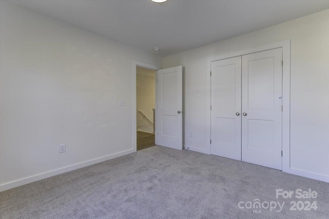 unfurnished bedroom featuring a closet and light colored carpet