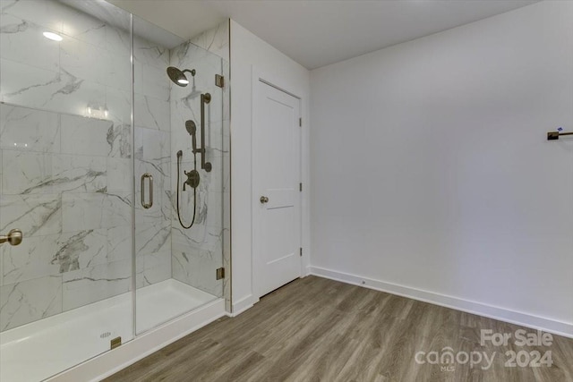 bathroom with a shower with shower door and wood-type flooring