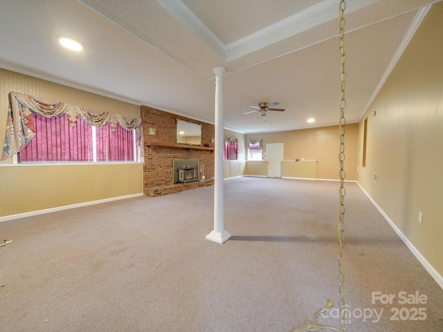 basement with carpet flooring, a wood stove, crown molding, and ceiling fan