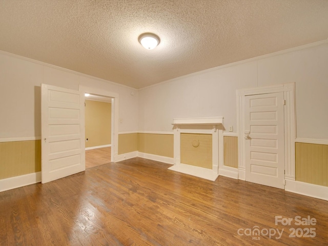 spare room featuring wood-type flooring, a textured ceiling, and ornamental molding