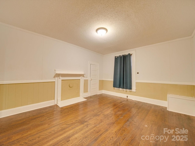 unfurnished living room featuring hardwood / wood-style floors, ornamental molding, and a textured ceiling