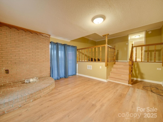 unfurnished living room featuring crown molding, a textured ceiling, and hardwood / wood-style flooring