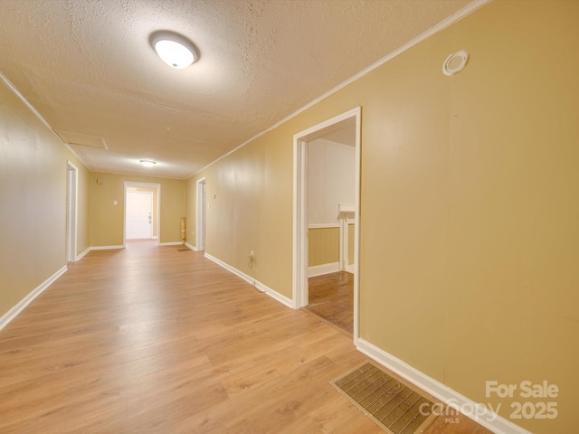 unfurnished room with light hardwood / wood-style floors, a textured ceiling, and ornamental molding