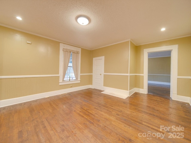 spare room with a textured ceiling, wood-type flooring, and crown molding