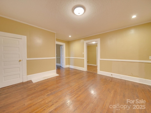 empty room featuring wood-type flooring, a textured ceiling, and ornamental molding