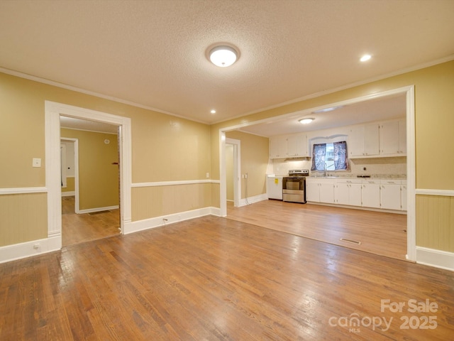 unfurnished living room featuring wood-type flooring, a textured ceiling, crown molding, and sink